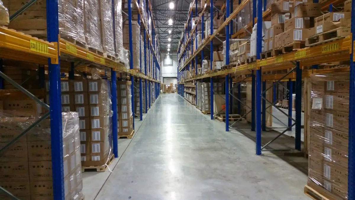 Allée d’entrepôt bordée de rayonnages chargés de cartons