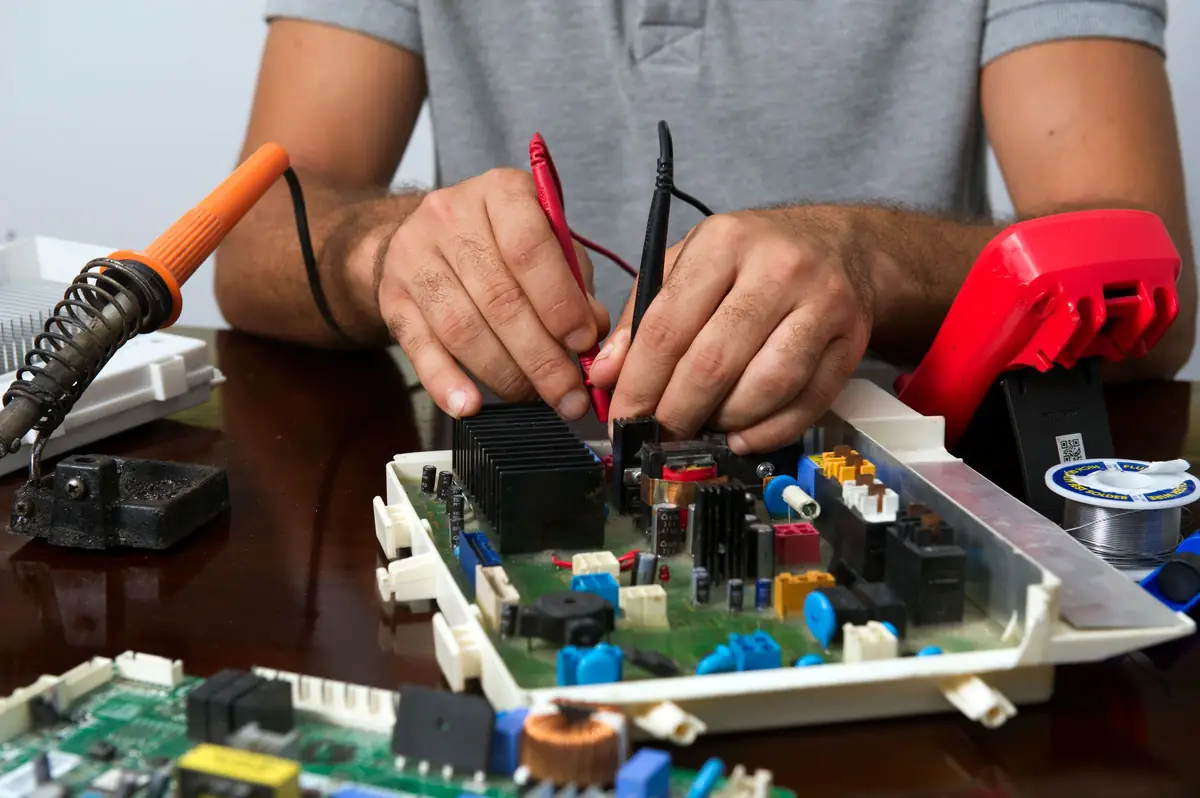 Technicien testant une carte électronique au multimètre